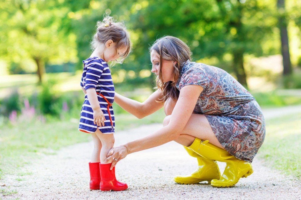 mother and little adorable child girl in rubber boots having fun