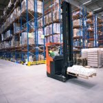 worker-operating-forklift-machine-and-relocating-goods-in-large-warehouse-center